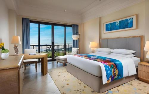 珠海市にあるChimelong Hengqin Bay Hotelのベッドと机と大きな窓のある寝室