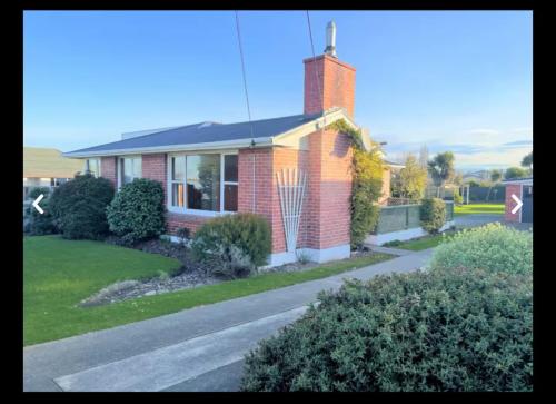 a red brick house with a street in front of it at Seaside Retreat in Timaru