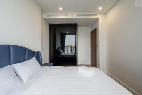 a bedroom with a white bed with a blue headboard at Lumiere Horizon Suites in Ho Chi Minh City