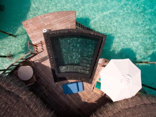 an overhead view of a swimming pool with an umbrella at Constance Halaveli in Hangnaameedhoo