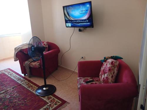 a living room with two chairs and a tv on the wall at Flores casas de playa in Alexandria