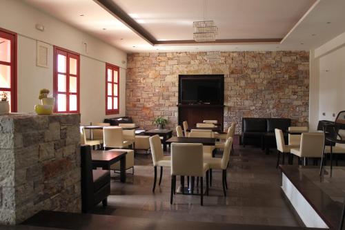 a restaurant with tables and chairs and a brick wall at Aposperides Hotel in Livadi