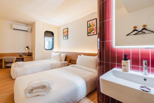 a hotel room with two beds and a sink at VELA be Bangkok Siam in Bangkok