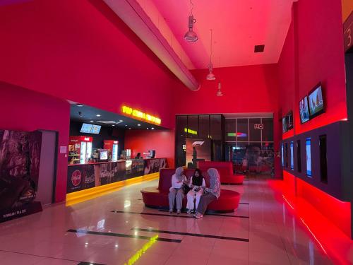 two people sitting on a couch in a red room at Times Hotel Brunei in Bandar Seri Begawan