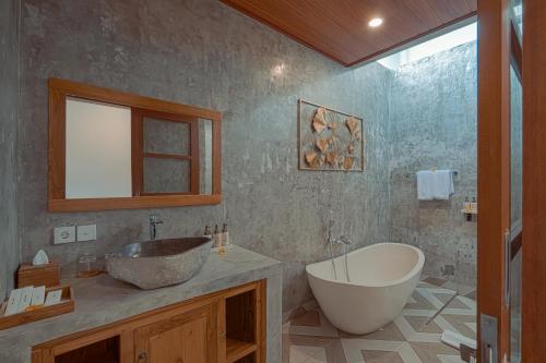 a bathroom with a tub and a sink and a bath tub at Matahari Lumbung Resort in Ubud