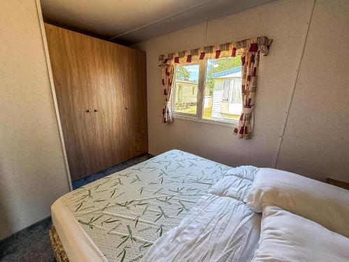 a small bedroom with a bed and a window at Homely Dog-Friendly Caravan At Valley Farm In Essex, Ref 46633V in Great Clacton