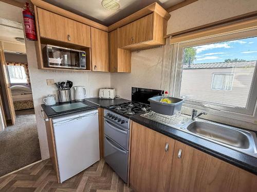a small kitchen with a stove and a sink at Homely Dog-Friendly Caravan At Valley Farm In Essex, Ref 46633V in Great Clacton