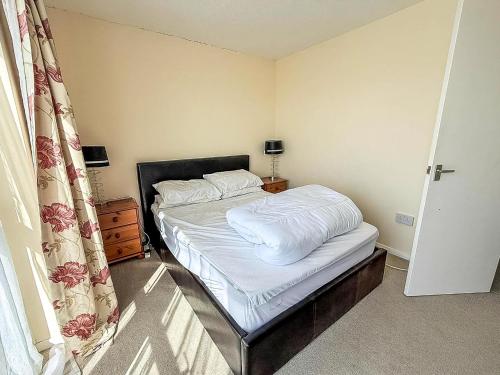 a small bedroom with a bed with white sheets at 5 Berth Chalet To Hire In Hemsby Near Hemsby Beach Ref 18117B in Hemsby