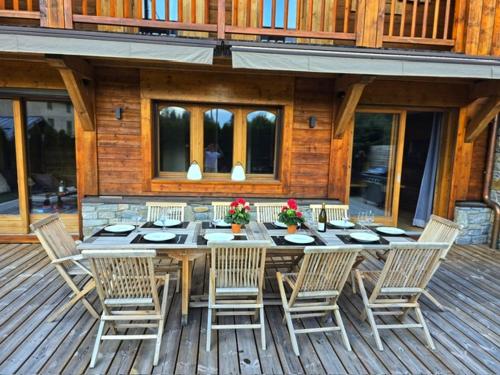 une table et des chaises en bois sur une terrasse dans l'établissement Amazing Chalet with Hot Tub Sauna and Panoramic View, à Chamonix-Mont-Blanc