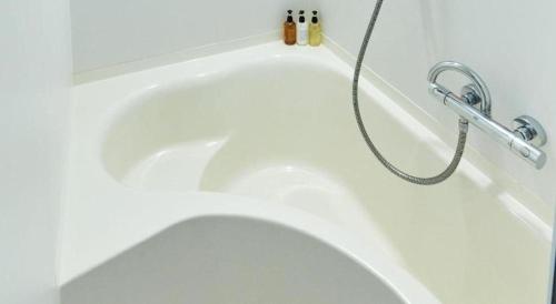 a white toilet in a bathroom with a hose at Hotel Edit Yokohama in Yokohama