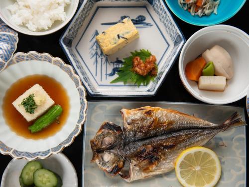 a table topped with plates of food with fish and vegetables at Kaihinsou Kamakura in Kamakura