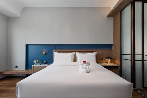 a white teddy bear sitting on a large bed at Arula Mianyang Jianshan Hotel-绵阳见山檀程酒店 in Mianyang