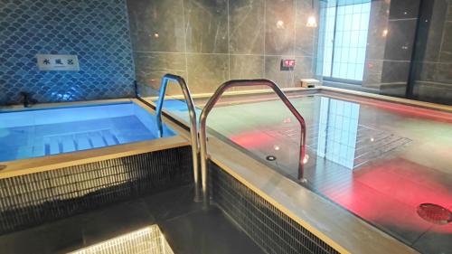 a swimming pool with a hot tub in a room at HOTEL LiVEMAX Honhachinohe Ekimae in Hachinohe