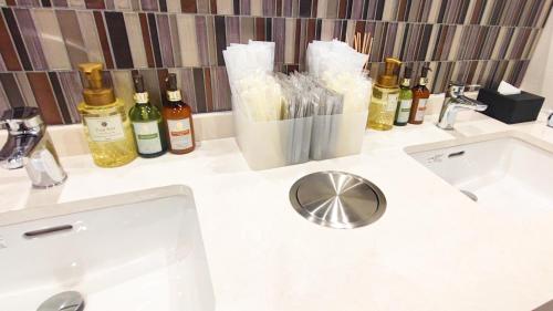 a bathroom counter with a sink and bottles of wine at HOTEL LiVEMAX Honhachinohe Ekimae in Hachinohe