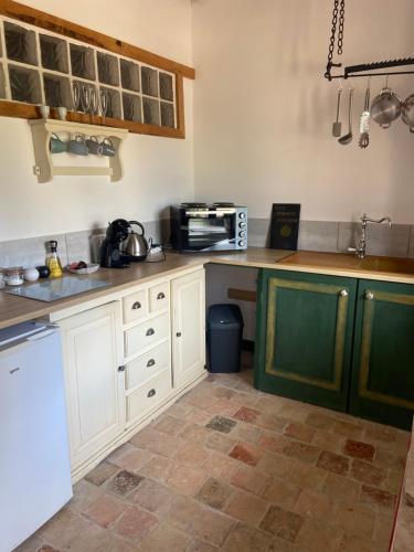 una cucina con mobili bianchi e un forno a microonde di Sunflower Cottage a Genneteil