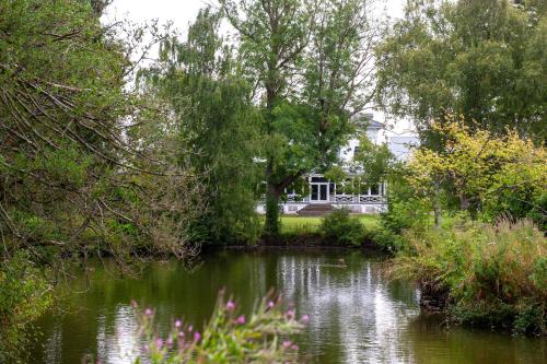 uitzicht op een vijver met een huis op de achtergrond bij Villas at Park Campus in Cheltenham