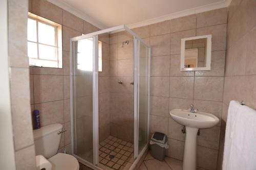 a bathroom with a shower and a toilet and a sink at Attaché Guest Lodge & Health Spa in Midrand
