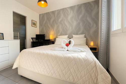 - une chambre avec un lit blanc et une serviette en forme de cœur dans l'établissement Villa Prestige Piscine, barbecue, Clim, Jardin top prosconciergerie, à Cournonterral