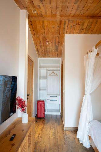 a bedroom with a wooden ceiling and a red suitcase at Maple house Hillside 3-BHK Without Pvt Pool & Open Pizzeria in Kangra