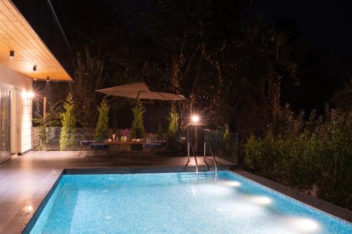 a swimming pool at night with a table and an umbrella at Maple house Hillside 3-BHK Without Pvt Pool & Open Pizzeria in Kangra