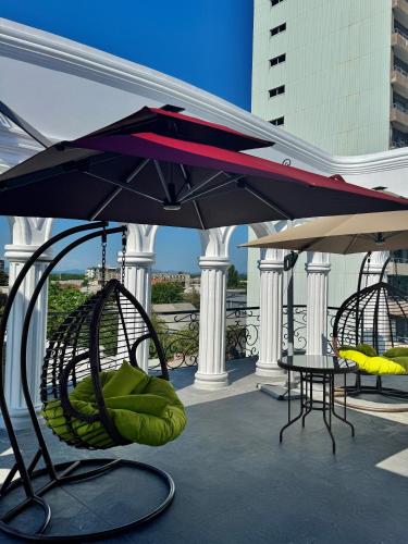 a patio with chairs and a table and an umbrella at Hotel Black Sea Kobuleti in Kobuleti