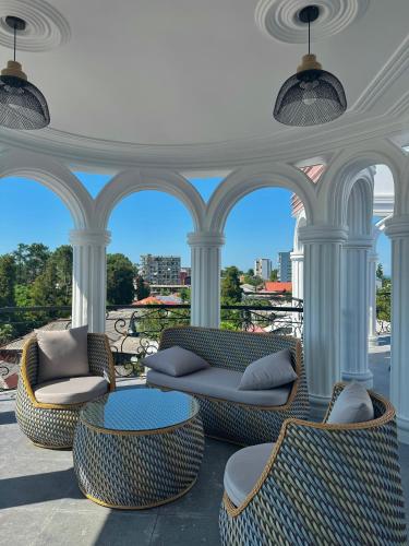 a porch with chairs and couches and a table at Hotel Black Sea Kobuleti in Kobuleti