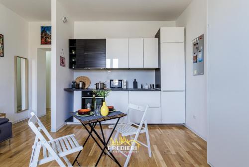 a kitchen with white cabinets and a table and chairs at Milano Centrale Near The Station & Wi-Fi in Milan