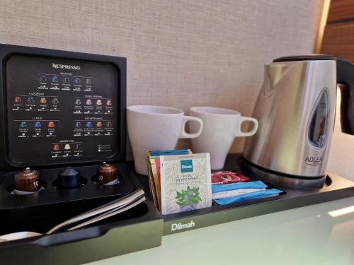 a counter with a coffee maker and cups on it at Warsaw Plaza Hotel in Warsaw