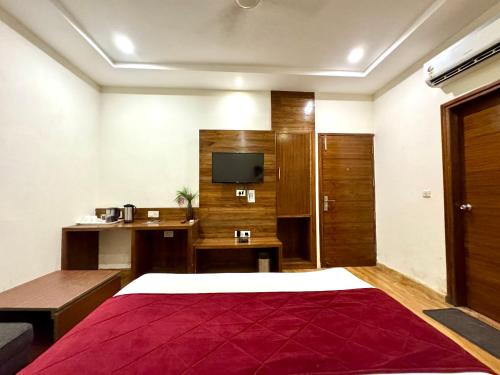 a bedroom with a bed and a desk and a television at Hotel Bahl Regency in Zirakpur