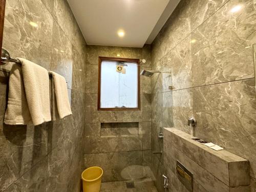a bathroom with a shower and a toilet and a window at Hotel Bahl Regency in Zirakpur