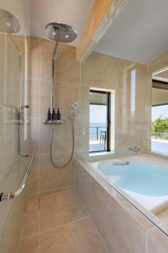 a bathroom with a tub and a shower with a window at L'Onde d'Azur Minamihayama in Yokosuka