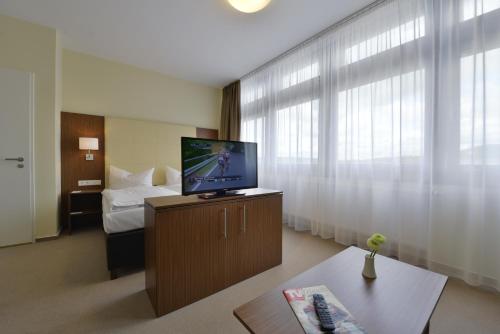 フルダにあるINVITE Hotel Fulda City Hauptbahnhofのテレビとベッドが備わるホテルルームです。