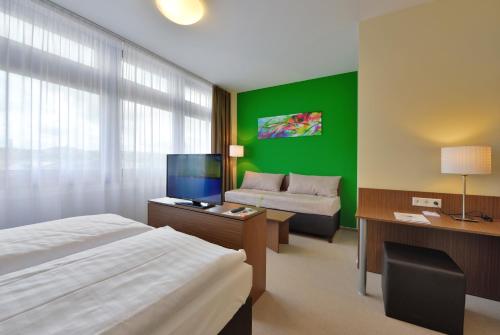 a hotel room with a bed and a green wall at INVITE Hotel Fulda City Hauptbahnhof in Fulda
