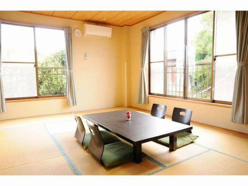 a dining room with a table and chairs and windows at Seaside Culinary Inn "Masaemon" - Traditional Dinner & Breakfast Included in Minamiboso