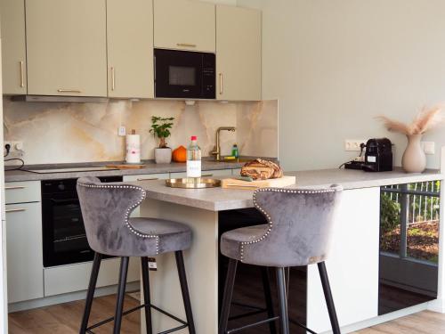 a kitchen with two bar stools at a counter at Living am Carlsplatz Apartment in Düsseldorf