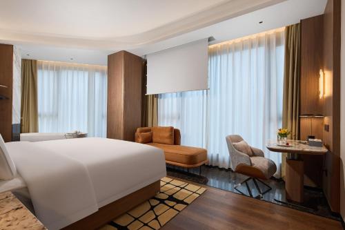 a bedroom with a large white bed and a desk at Arula Mianyang Jianshan Hotel-绵阳见山檀程酒店 in Mianyang