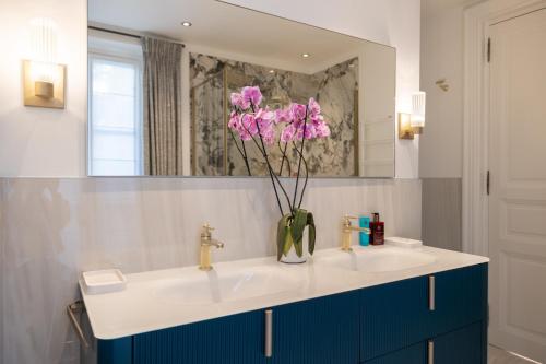 a bathroom with two sinks and a vase with pink flowers at Villa Soleil Riviera in Villefranche-sur-Mer