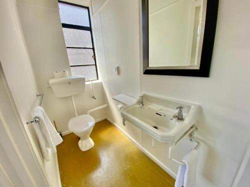 a white bathroom with a toilet and a sink at Law Courts Hotel in Dunedin