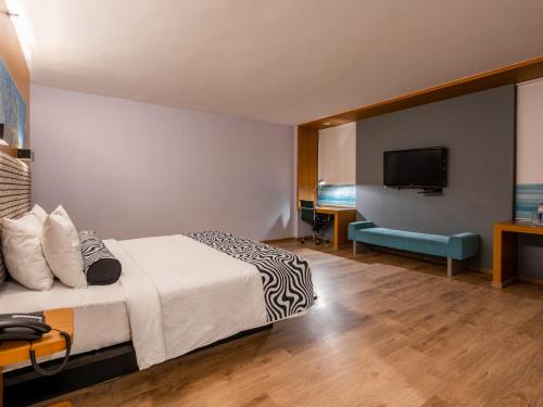 a hotel room with a bed and a flat screen tv at Sunday Hotel Chandigarh Zirakpur in Zirakpur