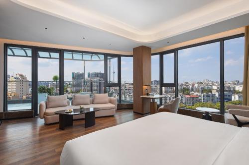 a bedroom with a bed and a couch and windows at Arula Mianyang Jianshan Hotel-绵阳见山檀程酒店 in Mianyang