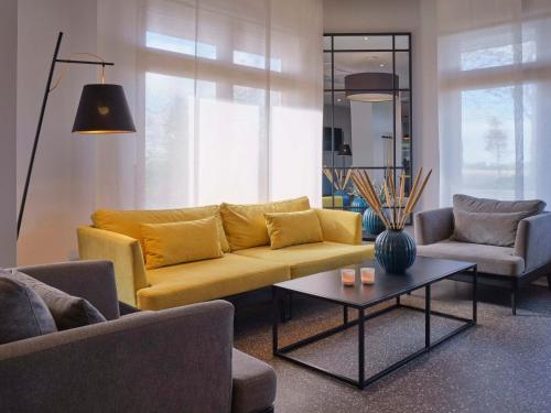 a living room with a yellow couch and a table at Classik Hotel Magdeburg in Magdeburg