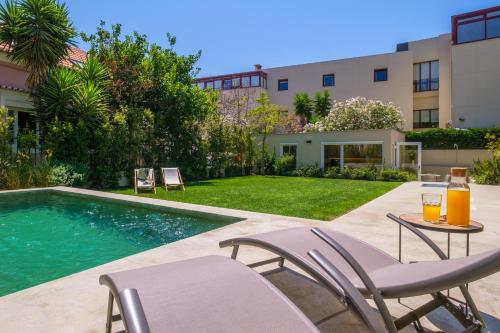 a swimming pool with two chairs and a table with drinks at Chalet Lídia Lodges in Estoril
