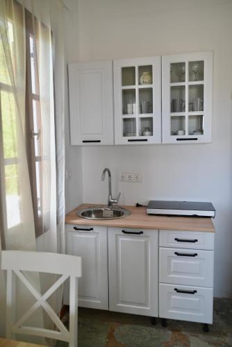 a kitchen with white cabinets and a sink at Rastoni Apartments Skiathos in Troulos