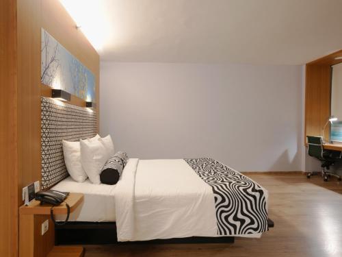a bedroom with a bed with a black and white blanket at Sunday Hotel Chandigarh Zirakpur in Zirakpur