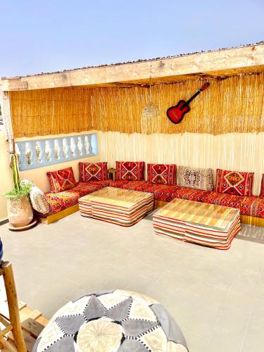a room with couches and a guitar on the wall at Waveside surf house in Tamraght Oufella