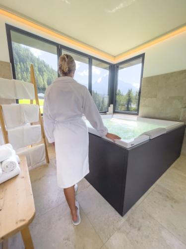 a woman standing in front of a bath tub at Turmchalet Adults Only in Braies