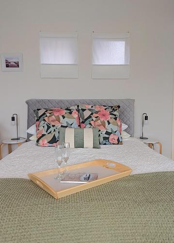 a tray with wine glasses and a plate on a bed at Boat Haven Studios in Goolwa