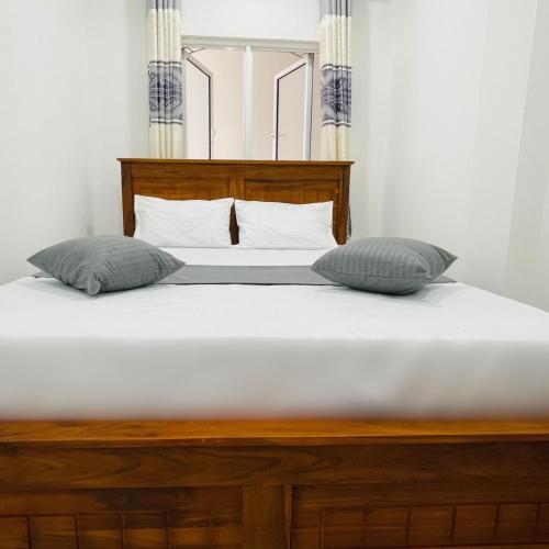 a bed with two pillows on top of it at Kandy Villa Grey in Talatuoya