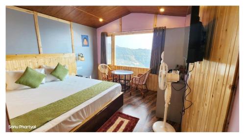 a bedroom with a bed and a television and a table at Hotel Himaaksh cottages In Sigri in Nainital