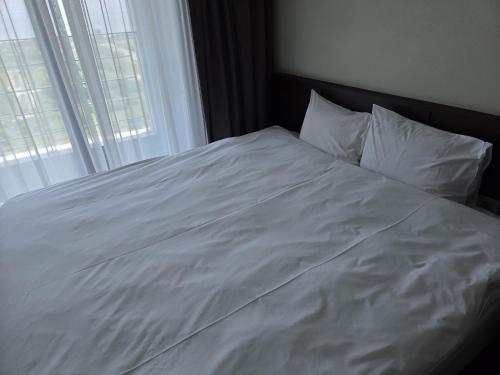 a bed with white sheets and pillows next to a window at Riviera Hotel Yeongjong in Incheon